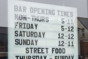 opening time sign using changeable letters in window of bar